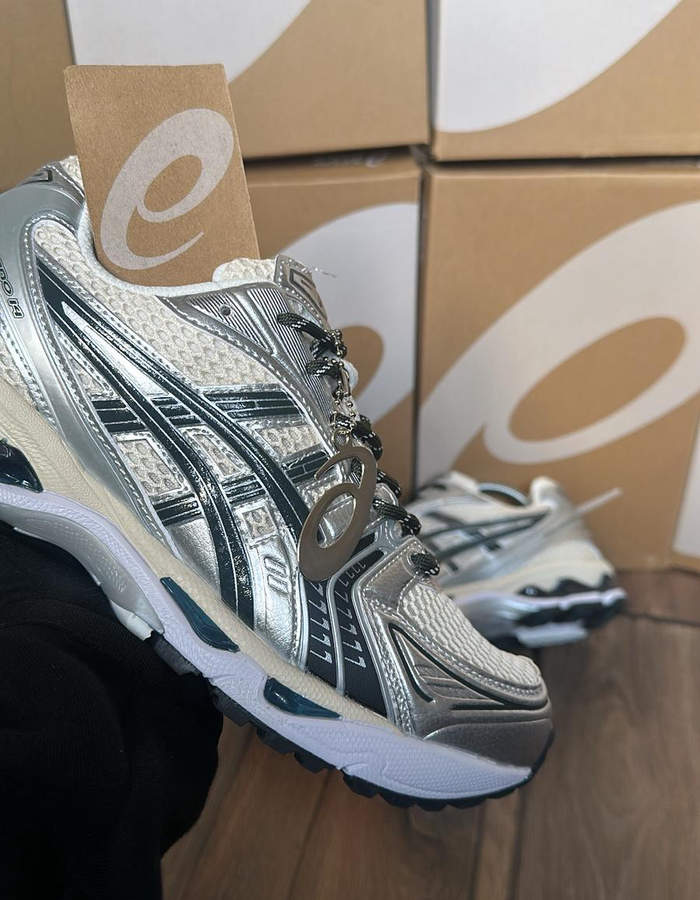 ASICS GEL-1130 silver black and white sneaker with branded boxes in the background