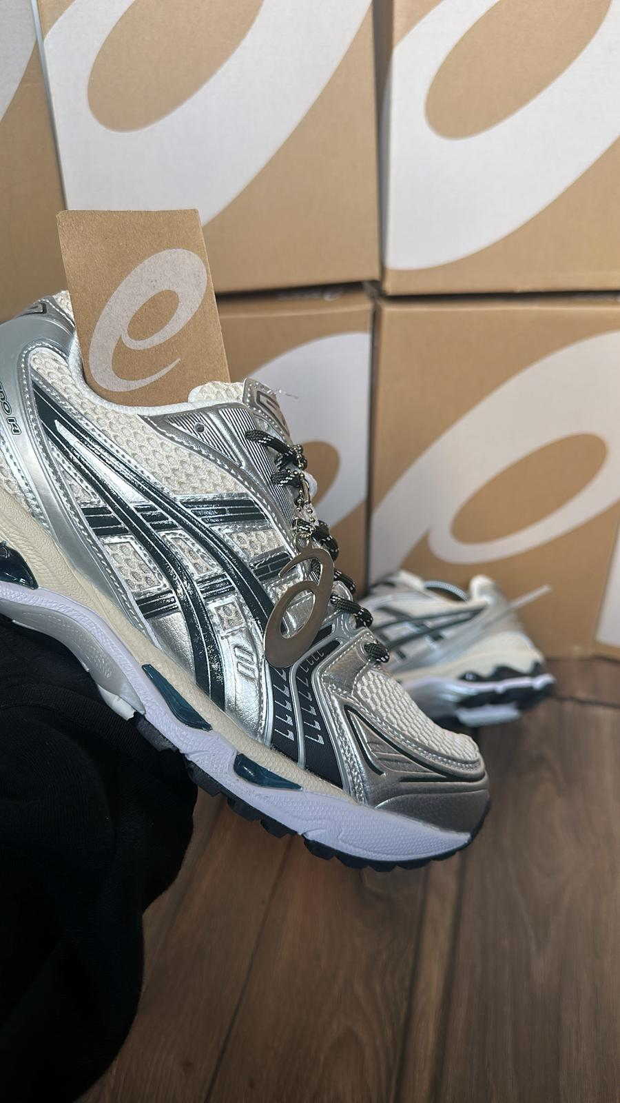 ASICS GEL-1130 silver black and white sneaker with branded boxes in the background